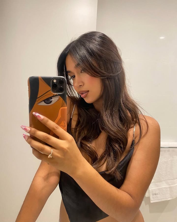 Woman posing with her hair in a loose half-up, half-down style.