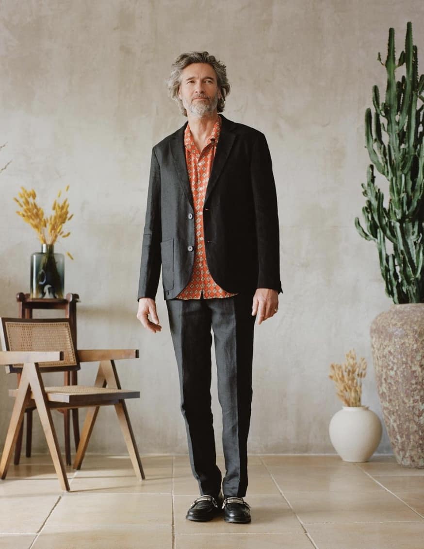 man posing wearing a dark suit and button up shirt