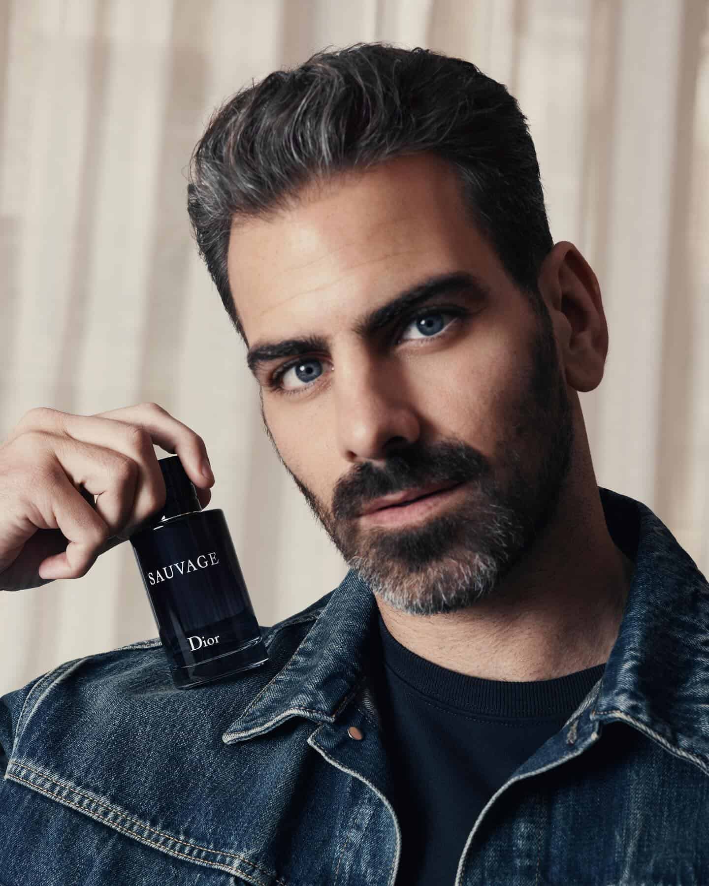 man holding a sauvage cologne on his shoulder